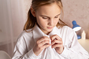 Little girl dressing in her school uniform in her room and getting ready to go to school