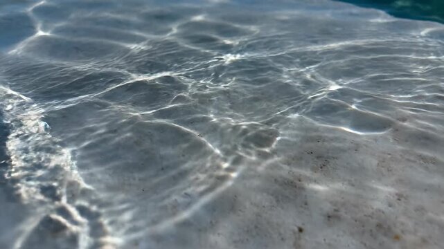 Subtly moving light caustics created by sun beams passing through slow motion water ripples onto a solid surface texture energy, pattern, ripples