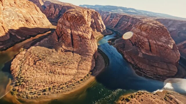 Sweeping drone aerial shot following a deep blue winding river carving an erratic nonlinear path through an arid canyon landscape river, curve, aerial