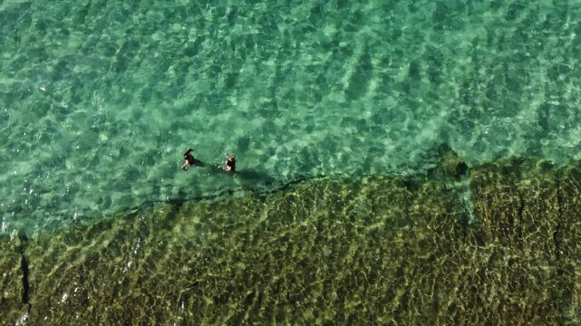 Aerial View of Two Women Swimming in the Clear Turquoise Waters of Sani Beach, Greece