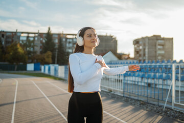 Woman stretching arm on running track with headphones