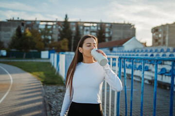 Young woman drinking water after workout on track