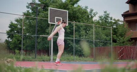 Young female basketball player stretching on an outdoor court, preparing for a practice session surrounded by lush greenery - Powered by Adobe