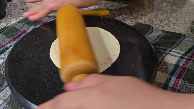 macro shot showing indian snack samosa being rolled with a rolling pin on a marble top shows puri roti bread also being made, popular Indian street food