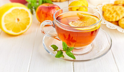 Tea with herbs fruits and cookies. Still life with hot drink, apple and nuts on a white wooden board in rustic style.