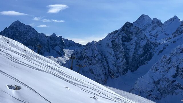 View of Dombay glaciers and mountain peaks in the winter sun. Panorama of the snow-capped Caucasus Mountains in sunny weather. Dombay-Ulgen and Moussa-Achitara mountains. Ski resort in Russia.