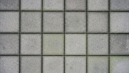 Grid of square grey concrete paving slabs with dark grout lines, forming a textured background.