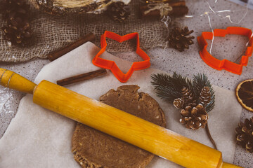 Christmas lifestyle with gingerbread cookies, dough and flour on dark background. Top view. Free space. Flat lay.
