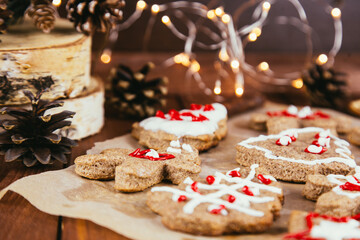 Christmas gingerbread cookies with icing in plate on festive rustic table with decorations, fir branches, golden illumination. Merry Christmas! Delicious gingerbread cookies, atmospheric time