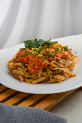 a plate of pasta noodles topped with tomato sauce mixed with meat, cheese, spices, onions and lettuce