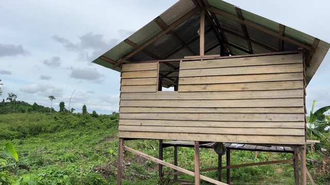 Wooden garden hut in a sunny rural landscape, surrounded by green plants and natural scenery. A peaceful farm setting with bright daylight and a calm outdoor atmosphere.