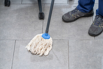 Close-up of an unrecognizable man mopping the office floor