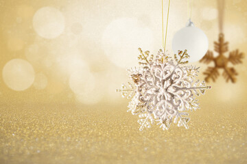 Sparkling Silver Glitter Snowflake and White Bauble on Icy Background. A stunning silver glitter snowflake ornament hanging near a white matte bauble against a highly textured, shimmering silver