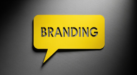 Close-up shot of yellow speech bubble with 'BRANDING' text on textured gray surface with top-down lighting, conveying business concept.