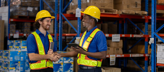Two warehouse workers wearing safety gear shaking hands and smiling during successful logistics operation. Teamwork, partnership, and collaboration in warehouse and supply chain industry.