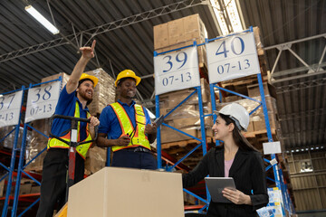 Team of warehouse workers and supervisor coordinating logistics and inventory management in distribution center. Professional teamwork concept in industrial supply chain and shipping operations.