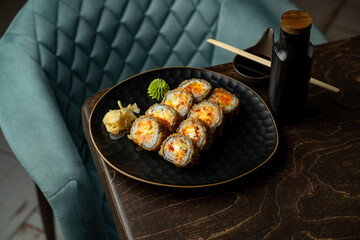 A plate of vibrant sushi rolls sits elegantly on a dark wood table. Soft green wasabi and ginger add a fresh touch, inviting a taste exploration of rich flavors