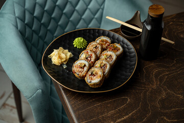 Savor a delightful presentation of sushi rolls on a sleek black plate accompanied by wasabi and pickled ginger, with chic wooden chopsticks ready for enjoyment