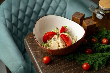 Bright red tomatoes and crisp greens blend beautifully in a rustic bowl placed on a wooden table. Fresh herbs and cherry tomatoes surround the dish in a welcoming cafe atmosphere