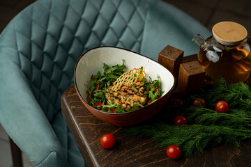 A vibrant garden salad filled with fresh greens, colorful vegetables, and a delicate honeycomb garnish sits on a wooden table beside a steaming cup of herbal tea