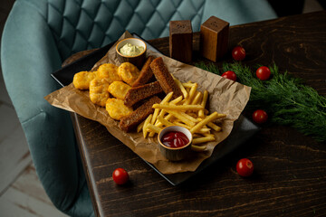 A tempting spread showcases golden chicken nuggets, crunchy fries, and a small bowl of ketchup nestled on rustic brown paper. Juicy cherry tomatoes and fresh greenery surround the scene