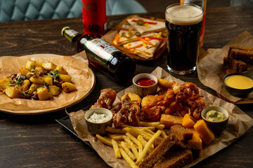 Gathered around a rustic table, savory dishes burst with flavors, featuring crispy fried delights, hearty potatoes, and chilled drinks, creating a perfect evening atmosphere