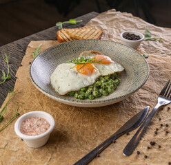 Plate of fried eggs on green peas puree