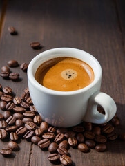 Obraz premium Fresh tasty espresso cup of hot coffee with coffee beans on dark background