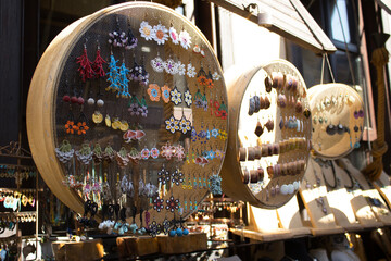 Assorted handmade earrings on round mesh frames and wooden stands under natural light; beads, metal, lace and glass in vivid colors, for fashion, retail display, craft education, artisan lifestyle fea