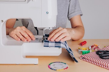Crafting with Precision: A Seamstress Operating a Sewing Machine While Working on a Fabric Project Surrounded by Tools and Materials
