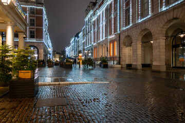 Walking on streets of Central London in Covent Garden decorated with Christmas lighting and green Christmas trees with garlands, December holidays in England