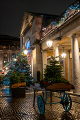 Walking on streets of Central London in Covent Garden decorated with Christmas lighting and green Christmas trees with garlands, December holidays in England