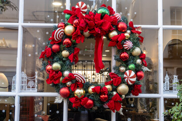Festive Christmas wreath on window decorated with Christmas lighting, balls, Christmas trees with...
