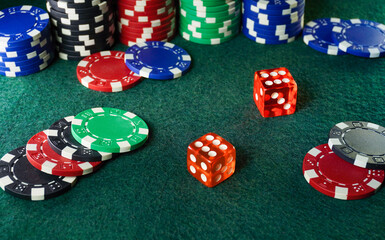 A vibrant layout of various poker chips in different colors surrounds two red dice on a green felt table. The setting suggests an engaging game night atmosphere with excitement