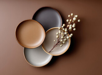 Four ceramic plates in neutral tones arranged on brown background with decorative branch, minimalistic and elegant tableware style