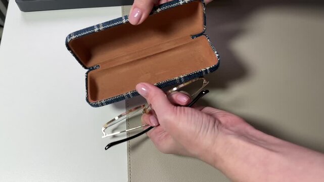 Female hand placing prescription glasses into protective case close up