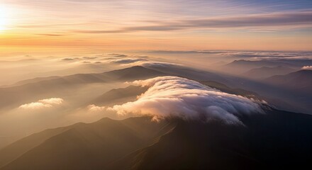 Aerial view of a mountain range with clouds at sunrise, creating a serene and majestic landscape.