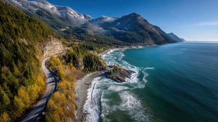 A breathtaking view of the coastline features a winding road surrounded by vibrant greenery and mountains. The ocean waves crash against the shore under a bright blue sky.