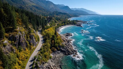 A beautiful coastal road winds along the shore surrounded by vibrant green trees. The clear blue ocean waves crash against rocky outcrops under a bright sky. Mountains rise in the distance.