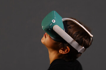 Boy using VR headset with two motion controllers, immersed in virtual reality gaming and focusing on interactive digital experience