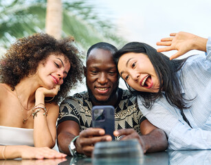 Portrait of a couple young people hangout in the city , sitting in a cpffee shop or bar table taking a selfie photo with a smartphone together and having fun.