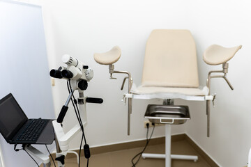Gynaecology, examination, medical clinic room with modern equipment, a chair, colposcope, laptop, and copy space.