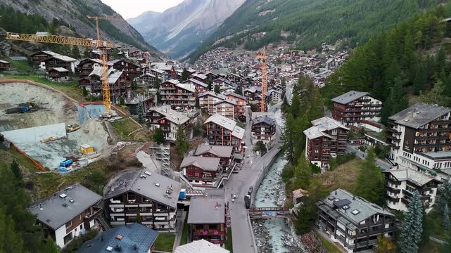 Aerial tracking shoot of Midday Zermatt with constructions crains visible city alpine village Switzerland

