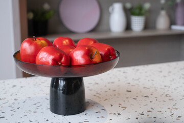 Red apples arranged in a modern decorative bowl on a stylish tabletop, highlighting healthy lifestyle, home decor, freshness, interior aesthetics, and natural food presentation in a cozy living space.