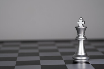 Silver king chess piece on a chessboard symbolizes leadership, strategy, decision-making, competition, and power, representing business planning, strategic thinking, and successful leadership concepts