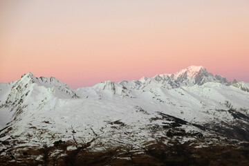 Snow-capped mountains with a pink sky at sunrise or sunset