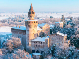 Aerial view of castle of Rivalta covered in winter snow with frosted trees and rural landscape, Trebbia Valley, Piacenza, Emilia-Romagna, Italy