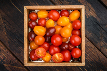 Colorful organic cherry tomatoes arranged in a wooden crate top view ideal for vegan recipes salad ingredients and grocery packaging.