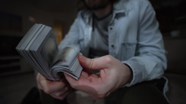 Hands performing a money fanning gesture with thick dollar stacks expressing wealth profit and make money. Hands Holding Cash, Wealth and Income concept. Money Thumbing with Financial Success
