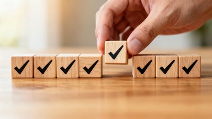 Hand placing wooden block with checkmark among a row of similar blocks on a wooden surface